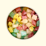 A tin container filled with an assortment of floral-inspired hard candies in white, purple, blue, and yellow colors.