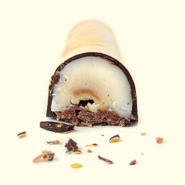 A gourmet chocolate bar cut open to reveal the coconut passionfruit filling. Handmade chocolate sweet treats by online chocolate store Topogato.