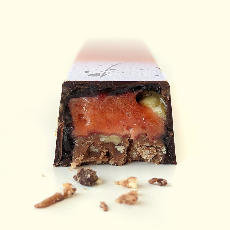 A gourmet chocolate bar cut open to reveal the strawberry almond filling. Handmade chocolate sweet treats by online chocolate store Topogato.