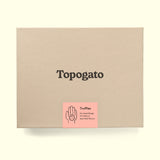 A truffle box with a logo of gourmet chocolate company Topogato shown from the top down. The chocolate gift box has a label that details the contents in a playful way with a lively illustration of a hand holding a sweet treat.