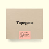 A truffle box with a logo of gourmet chocolate company Topogato shown from the top down. The chocolate gift box has a label that details the contents in a playful way with a lively illustration of a hand holding a sweet treat.