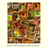 A close-up image of colorful chocolate truffles. Each sweet treat has a kraft colored candy cup, and they're all placed inside a chocolate gift box.