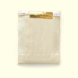 A handmade chocolate bar wrapped up for chocolate delivery in a cream sleeve from online chocolate store Topogato shown from the top down with a gold nutrition label.