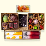 A top-down view of a chocolate gift box from online San Francisco chocolate store Topogato. A truffle box sits next to colorful gourmet chocolate bars in yellow, red, and dark brown.